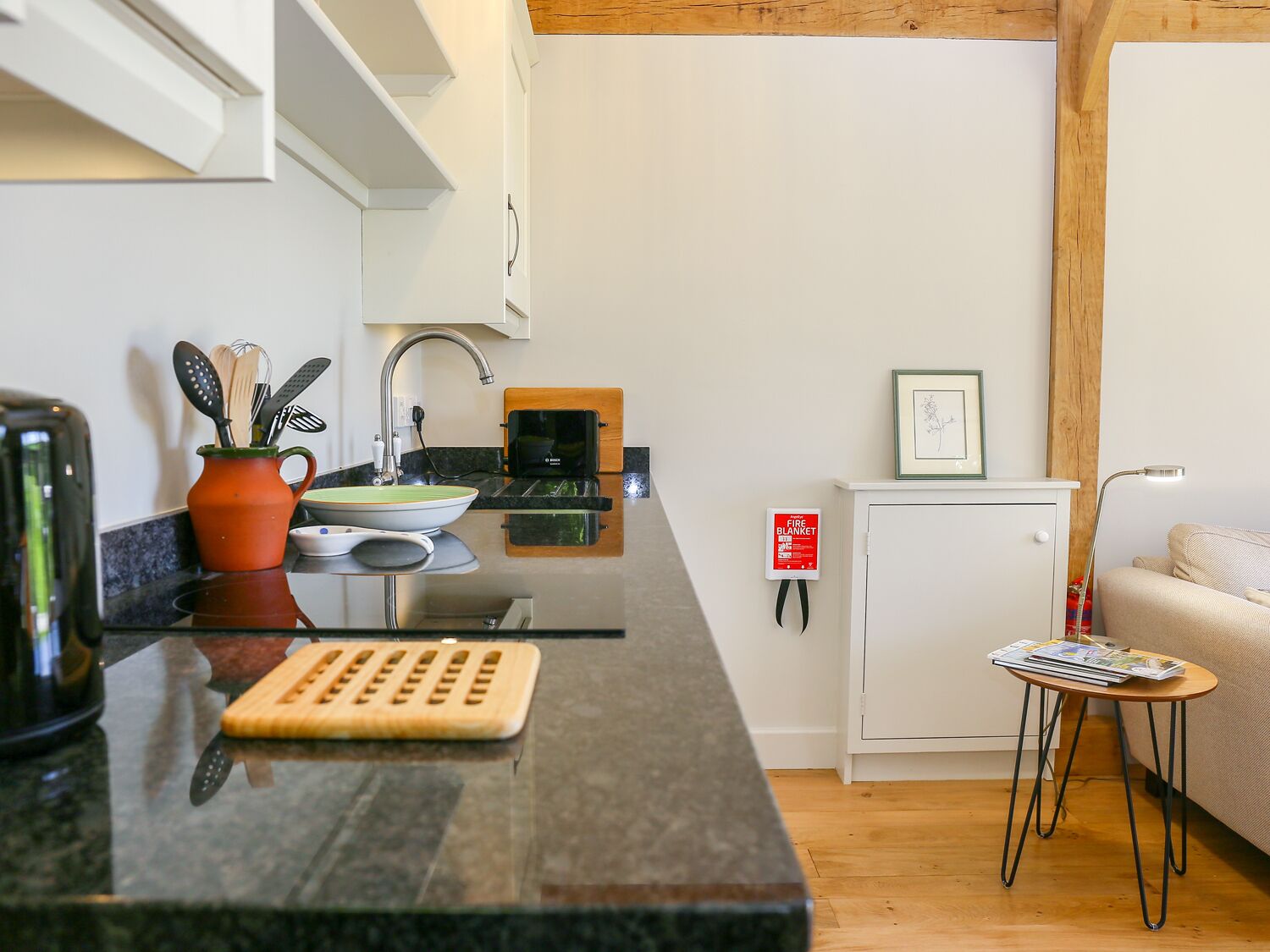 A compact kitchen with a sink, a coffee machine, and a small cabinet.