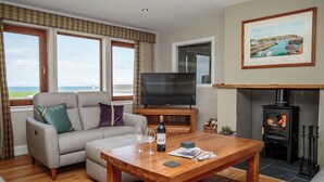 Ein Wohnzimmer mit einer Couch, einem Holztisch, einem Fernseher, einem Kamin und einem Gemälde an der Wand.