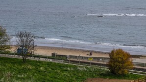 Una playa con una valla, un edificio pequeño y un área con césped.