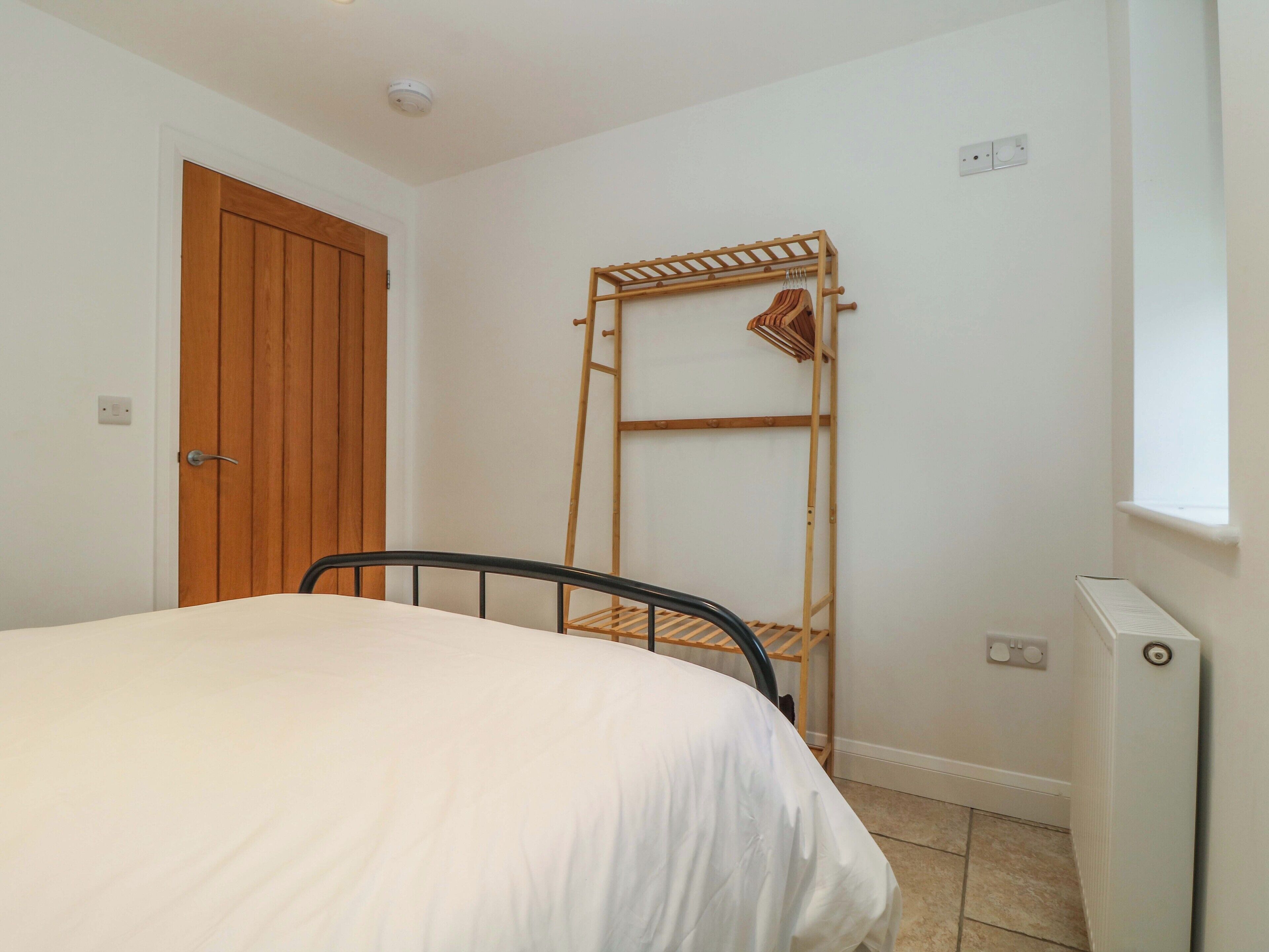 Een slaapkamer met een bed, een houten deur, een radiator en een raam.