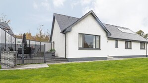 Ein modernes Haus mit großem Fenster, Balkon und gepflegtem Rasen.