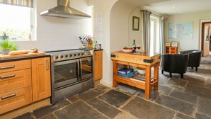 A modern kitchen with a built-in oven, a stainless steel range hood, and a wooden countertop. - Pen y Lon (Pentraeth)