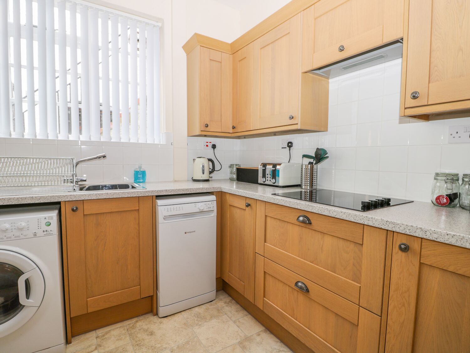 A compact kitchen with wooden cabinets, a dishwasher, a microwave, and a toaster.