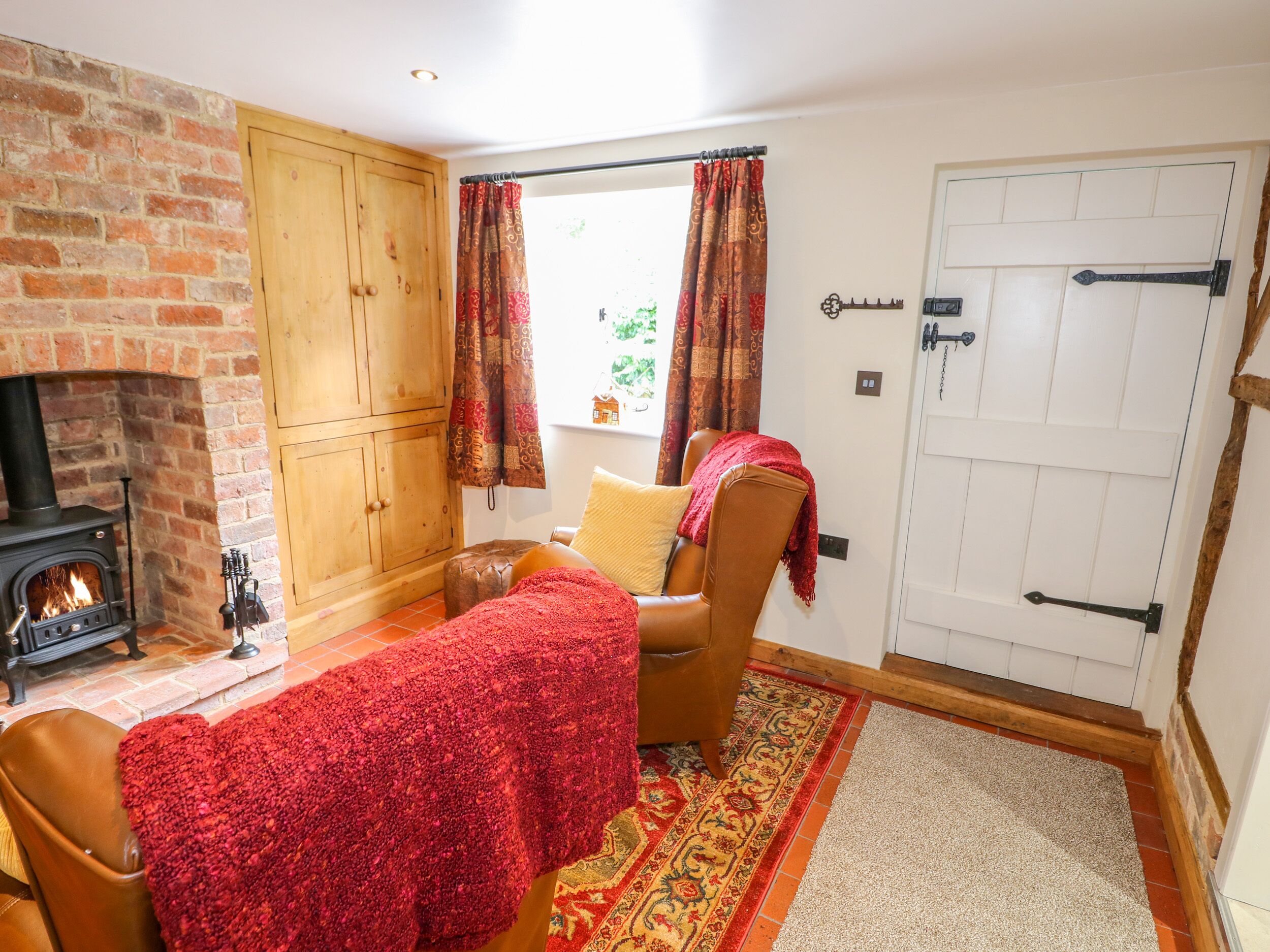 A cozy room with a brick fireplace, a wooden wardrobe, a comfortable chair, and a door with a handle.