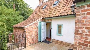 A brick house with a tiled roof, a white door, and a small window. - Lizzies Cottage (Horncastle)