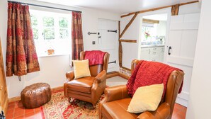 A cozy room with two leather armchairs, a patterned rug, and a wooden bench. - Lizzies Cottage (Horncastle)
