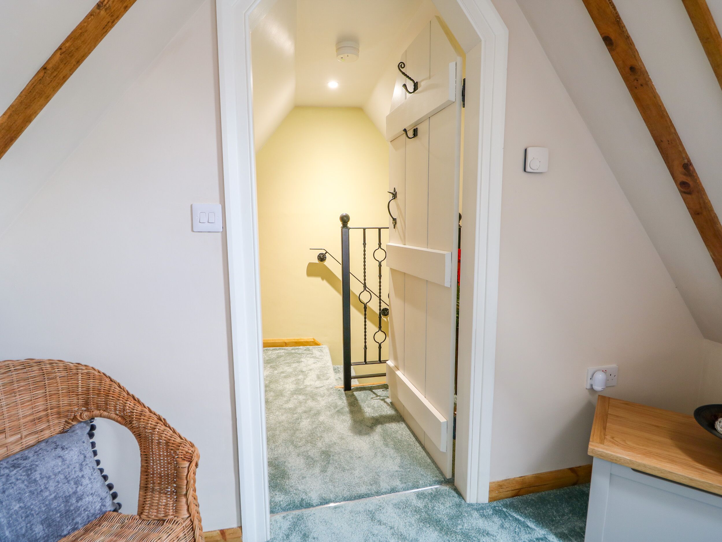 Un pasillo estrecho con techo de madera y una puerta blanca que da a una habitación.