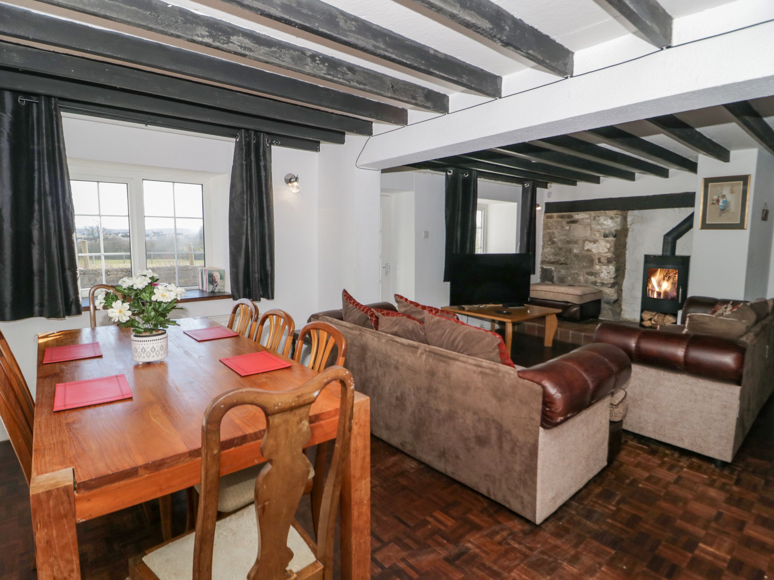 A spacious living area with a wooden dining table, sofas, and a fireplace.