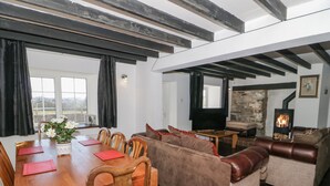 A spacious living area with a wooden dining table, sofas, and a fireplace.