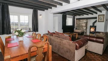 A spacious living area with a wooden dining table, sofas, and a fireplace.