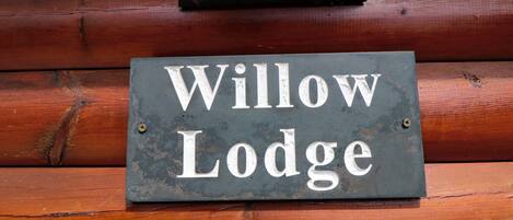 A sign with the text "Willow Lodge" mounted on a wooden wall.
