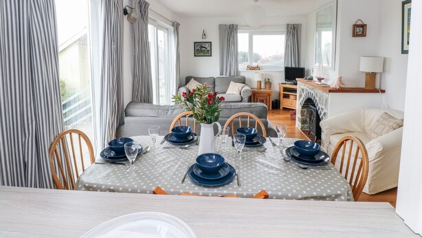 Ein Essbereich mit einem Tisch für vier Personen, einer Couch, einem Fernseher und einem Kamin.