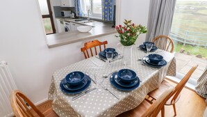 Ein Essbereich mit einem Tisch in Punkte-Muster, blauem Geschirr und einem Blumenstrauß.