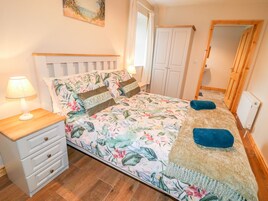 Un dormitorio con cama, mesita de noche, cómoda, armario y espejo.