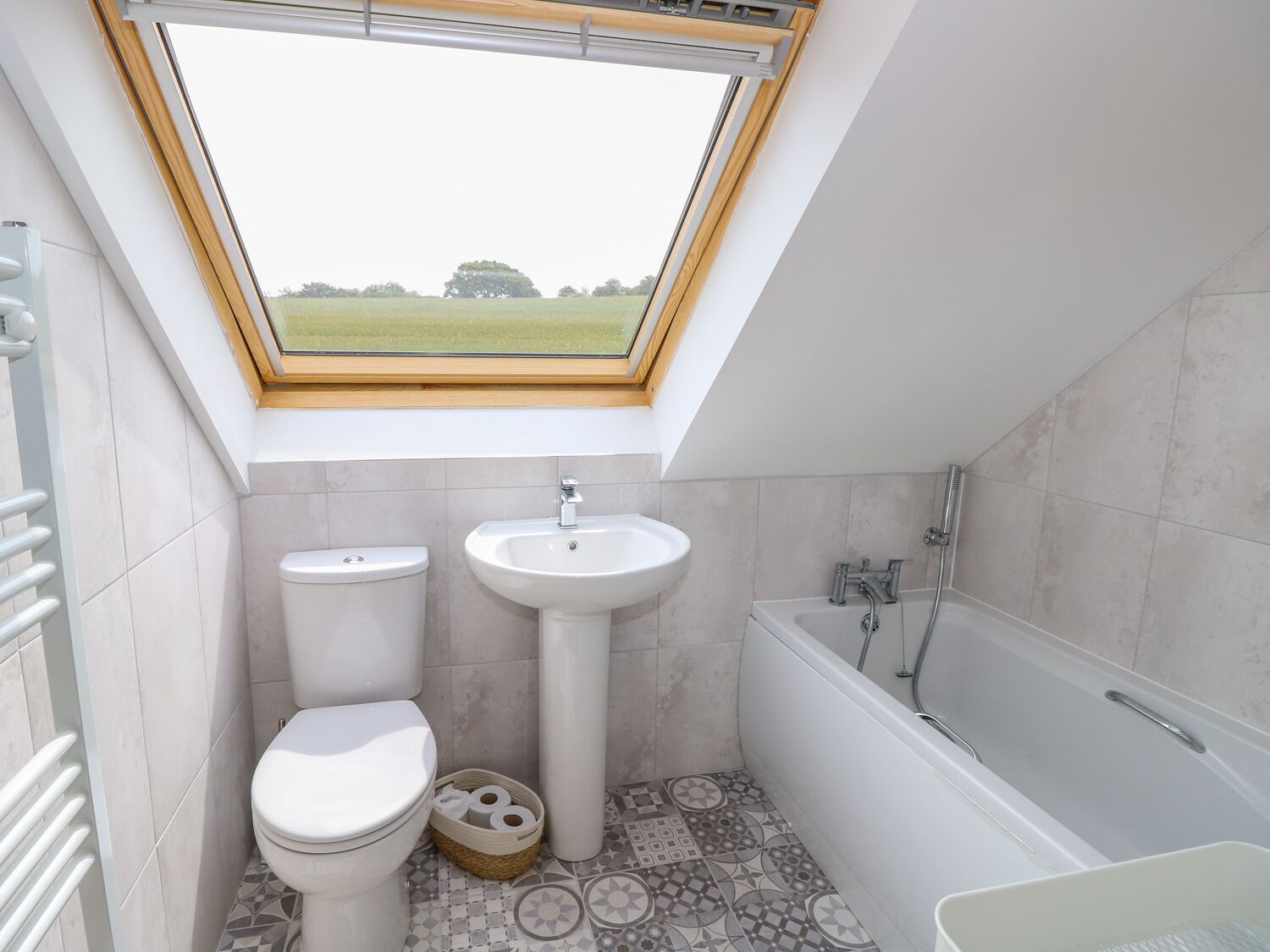 A bathroom with a skylight, a toilet, a sink, and a bathtub.