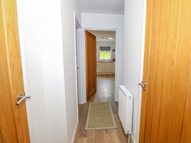 Un pasillo que conduce a una cocina con suelo de madera y un radiador.