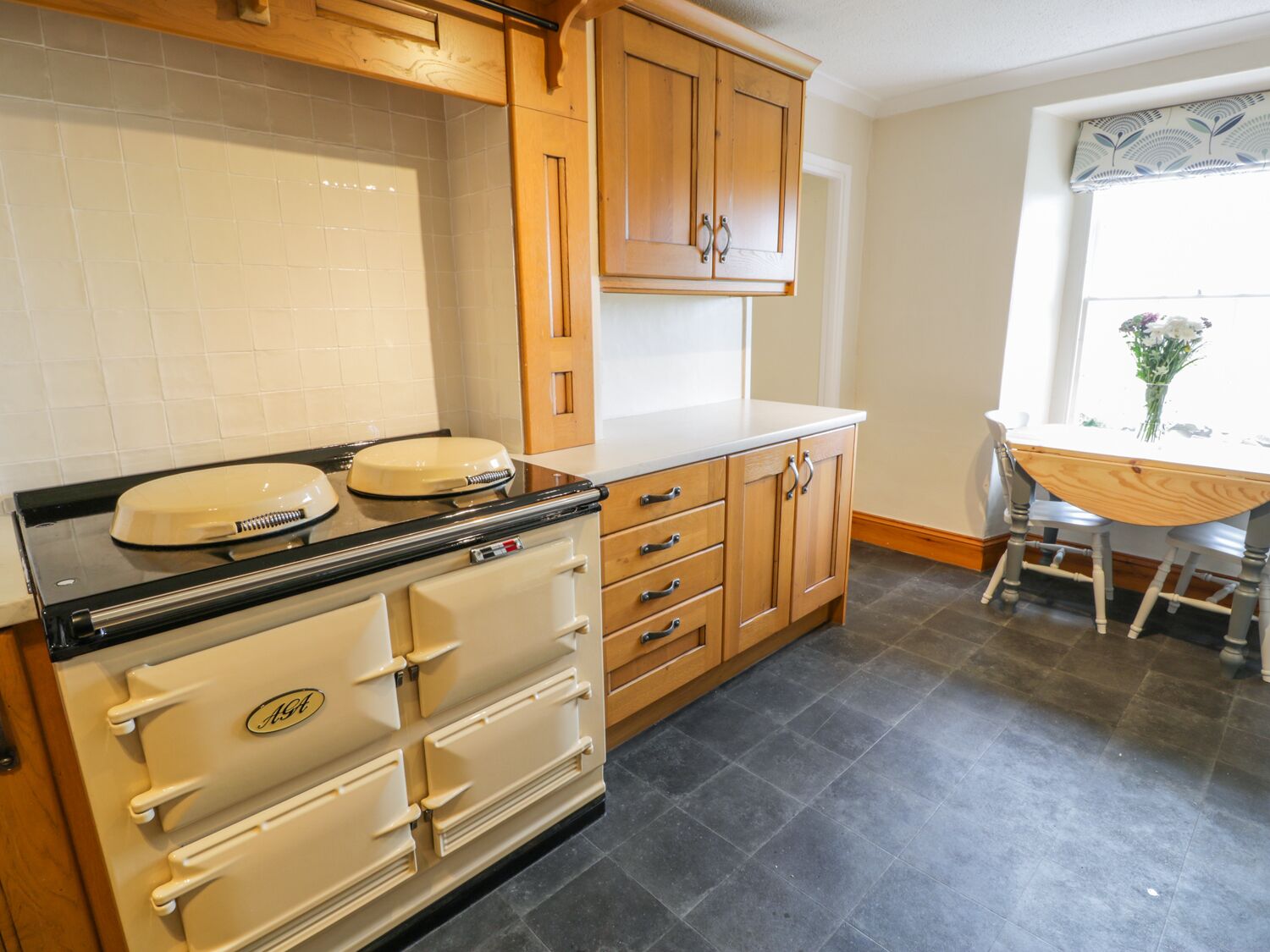 A kitchen with wooden cabinets, a stove, and a dining table with chairs.