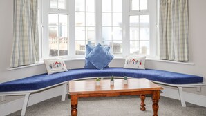 A room with a bay window seating area, white walls, and a wooden table.