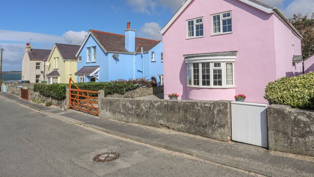 A row of colorful houses along a coastal road with a clear sky.