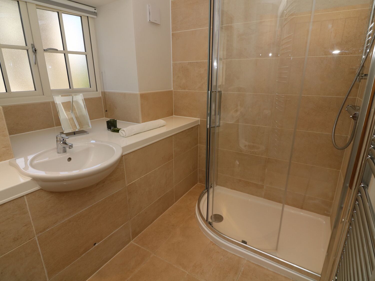 A bathroom with a sink, mirror, and shower.