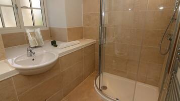 A bathroom with a sink, mirror, and shower.