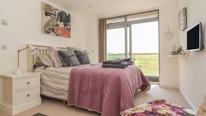 A bedroom with a bed, bedside table, and a window with a view. - 8 Cribbar (Newquay)