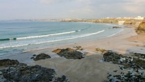 A coastal beach with rocky outcrops, a sandy shore, and a clear view of the ocean. - 8 Cribbar (Newquay)