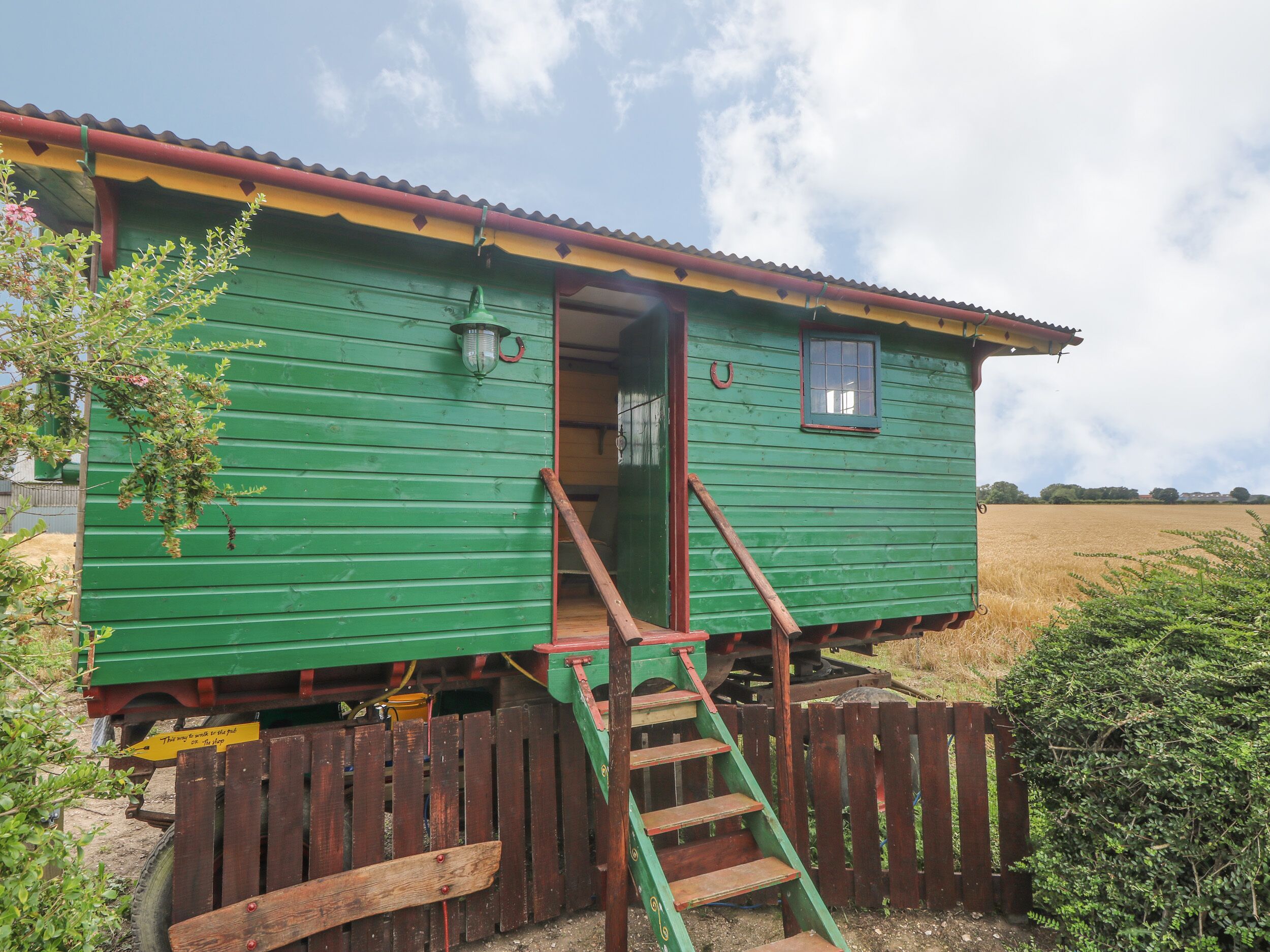 A green wooden house with a small porch, a window, and a door.