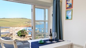 A dining area with a table set for two, overlooking a scenic coastal view. - The Reach (Kingsbridge)