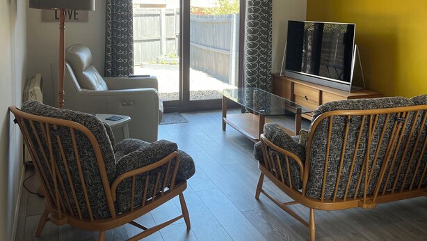 A living room with two wicker chairs, a sofa, a TV, and a lamp. - Village Retreat (Ely)