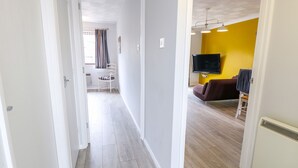 A hallway leading to a living area with a TV, a chair, and a sofa. - Village Retreat (Ely)