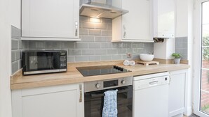 Eine moderne Küche mit weißen Schränken, einer Mikrowelle, einem Backofen und einem Geschirrspüler.