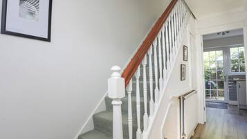 A staircase with white balusters and a wooden handrail, leading to a door with a glass panel.
