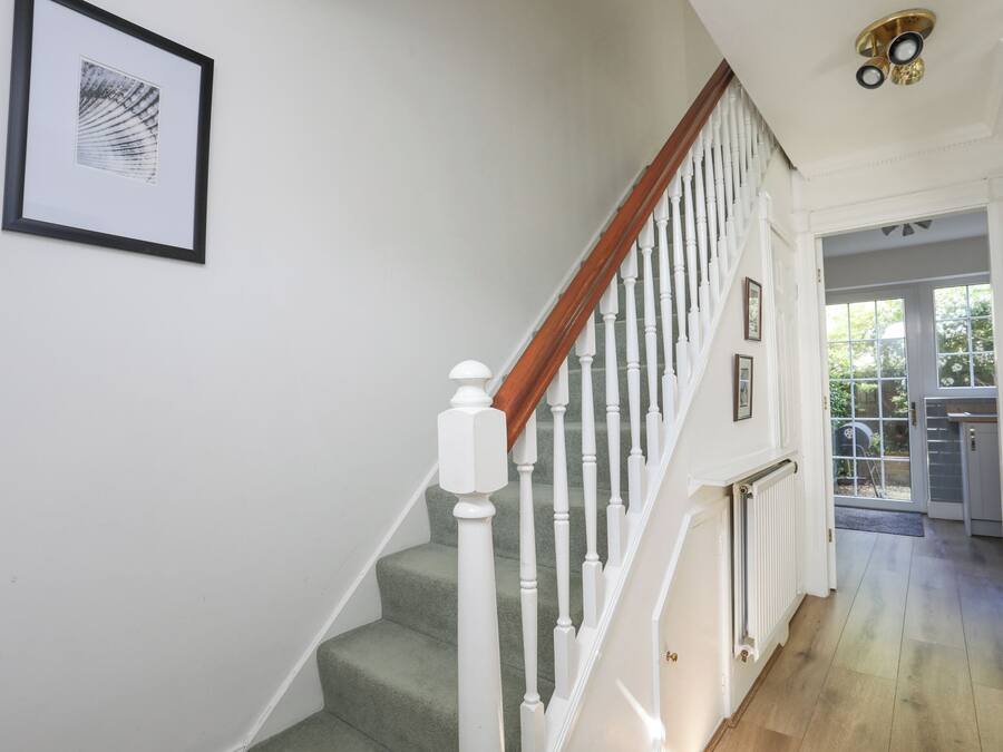 A staircase with white balusters and a wooden handrail, leading to a door with a glass panel.