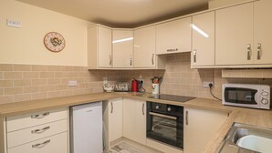 A compact kitchen with a dishwasher, oven, microwave, and a toaster. - Berrys Place Farm Cottage (Gloucester)