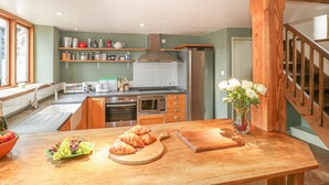 Una cocina con vigas de madera, encimera de madera, un lavabo, una estufa y un refrigerador.