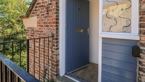 Un bâtiment en briques avec une porte bleue et une fenêtre ornée de motifs métalliques.