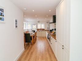 A modern kitchen with wooden flooring, white cabinetry, and a dining area with a table set for four.