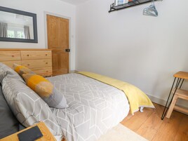 A bedroom with a bed, wooden dresser, and a door.