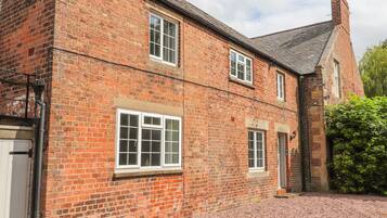 A traditional brick building with multiple windows and a gravel driveway.