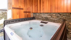 A hot tub with stone walls and wooden paneling. - The Boat House at Louper Weir (Windermere)