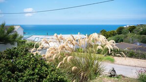 A coastal view with a grassy area, a statue, and a clear blue sky. - Blue Bay Beach House (Newquay)