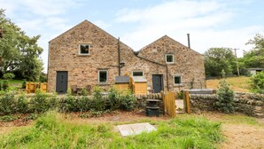 Une ferme en pierre comprenant deux bâtiments principaux, une clôture en bois et un jardin.
