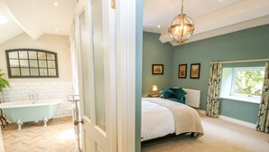 Une chambre à coucher avec un lit, une fenêtre avec des rideaux, un radiateur et une table de chevet avec une lampe.