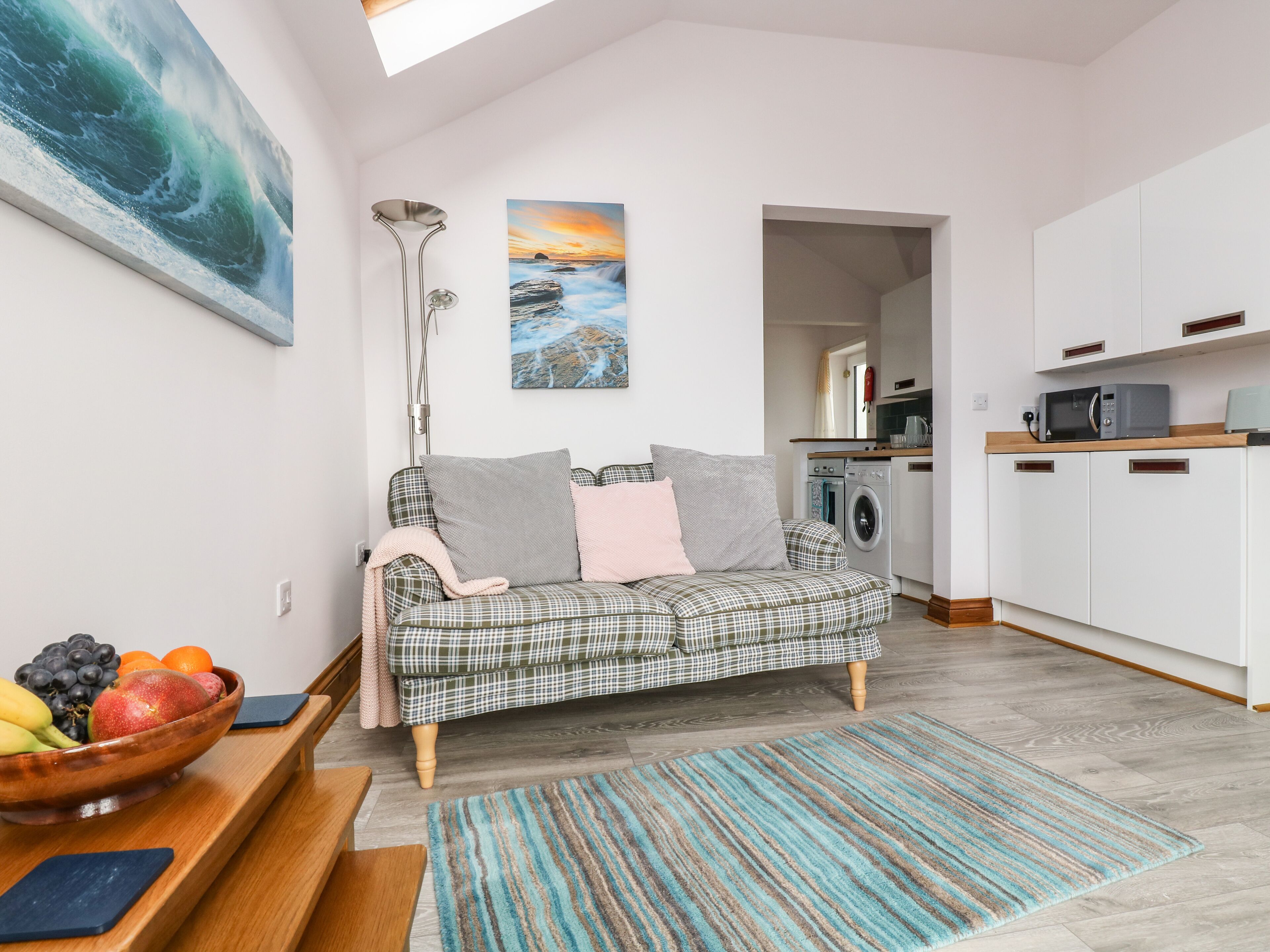 Un salon moderne avec un canapé à carreaux, un panier de fruits et un tapis rayé.