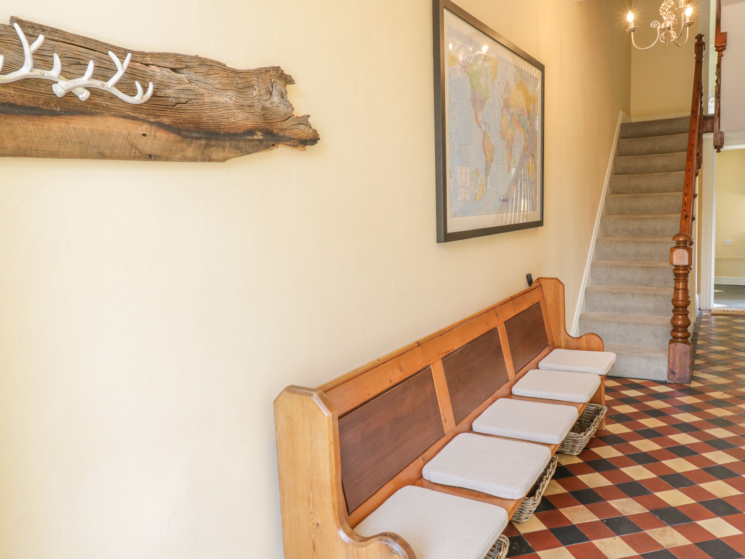 Un banc en bois avec des assises rembourrées, une carte du monde accrochée au mur et un escalier dont le sol est orné de motifs.