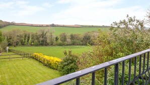 A rural landscape with a grassy field, trees, and a wooden fence. - Forget-me-not (St. Columb Major)