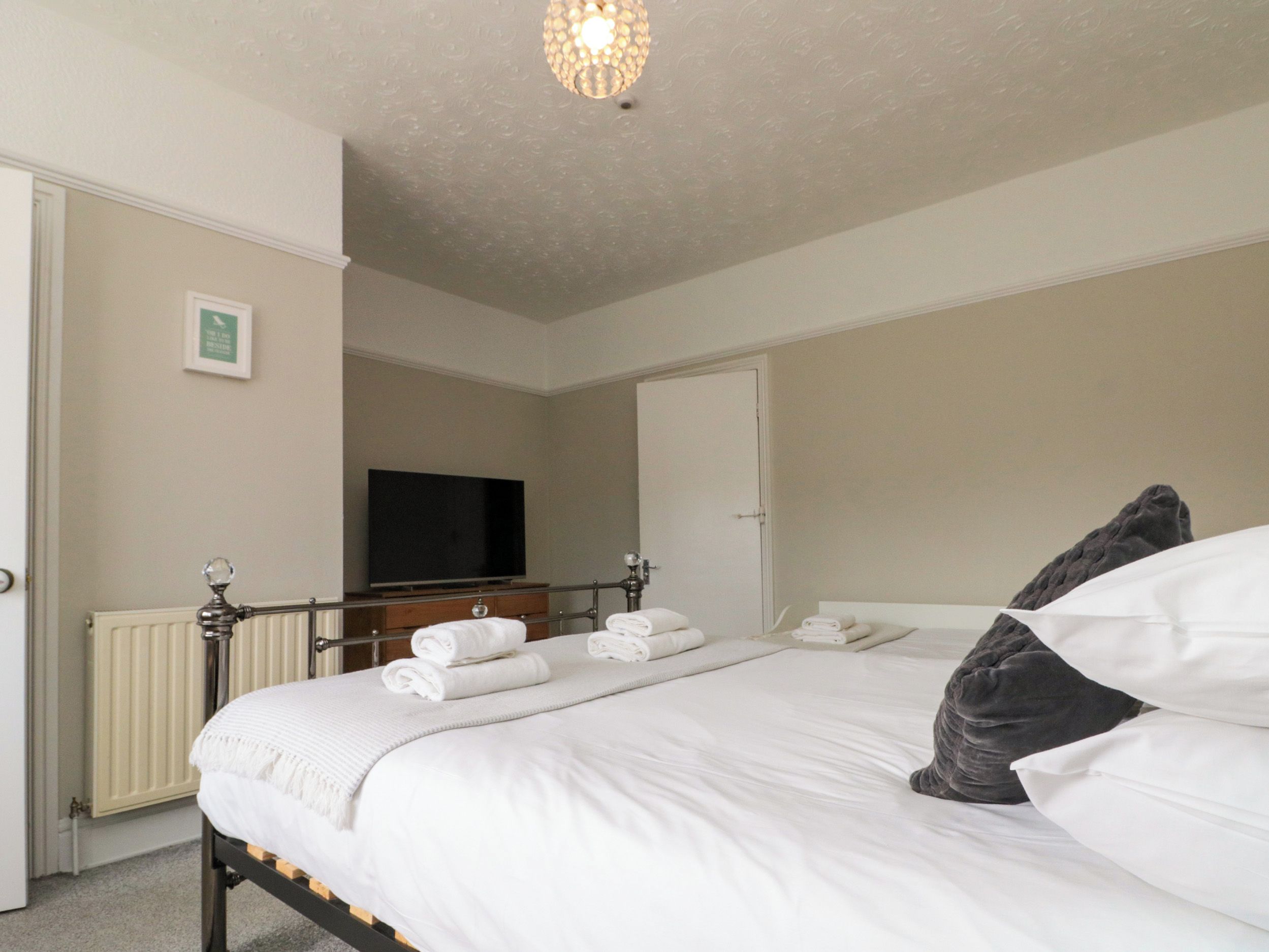 Habitación de hotel con cama, televisor y radiador.