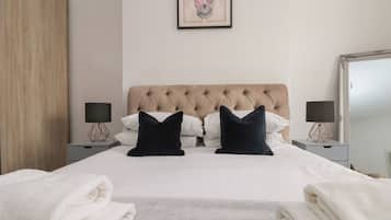 Ein Hotelzimmer mit einem großen Bett, zwei Nachttischen mit Lampen, einem gerahmten Kunstwerk an der Wand und einem Kleiderschrank.