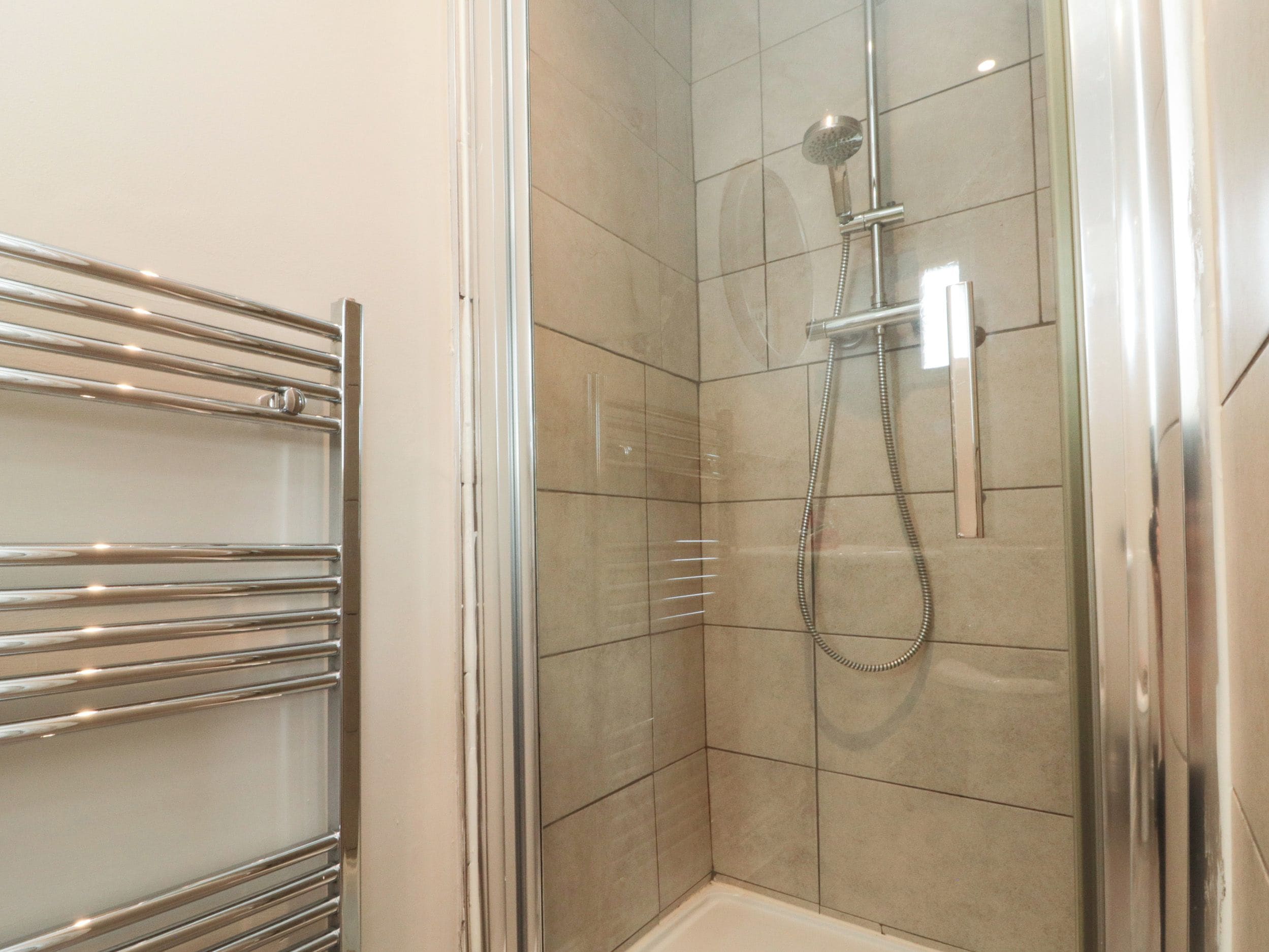 Une douche équipée d’un pommeau de douche à main et d’un robinet fixé au mur.